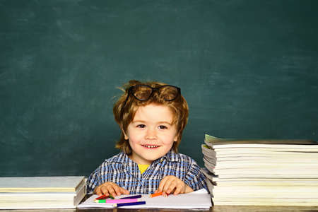Funny little boy pointing up on blackboard. Little student boy happy with an excellent mark....