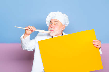 Senior Chief cook, blackboard menu, copy space. Senior male chief cook in uniform holding empty...