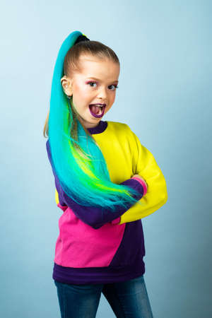 Colorful children. Beautiful little girl dressed in color jacket. Standing on the isolated gray background. Funny child face.の写真素材