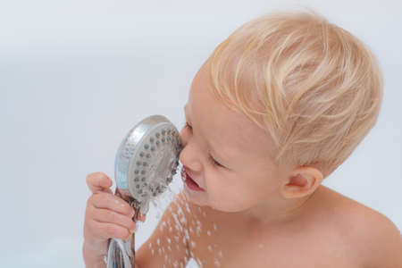Happy little boy in bath. Happy laughing baby taking a bath playing with foam bubbles. Pretty smiling little boy taking a bath with soap suds.の写真素材
