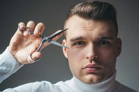Barber glossy hairstyle hold steel scissors. Create your style. Macho confident barber cut hair. Barbershop service concept. Professional barber equipment. Cut hair. Man strict face hold scissorsの写真素材