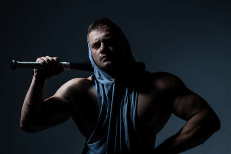 Dangerous muscular man with baseball bat ready for fight.