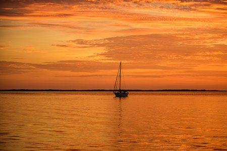 Boat on the sea at sunset. Sailboats with sails. Ocean yacht sailing along water.