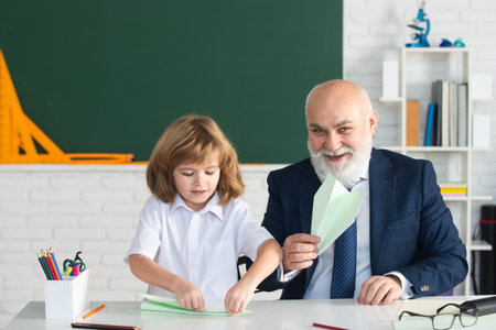 Happy kid in school. Teacher with pupil with airplanes. Education, teachering, elementary school.