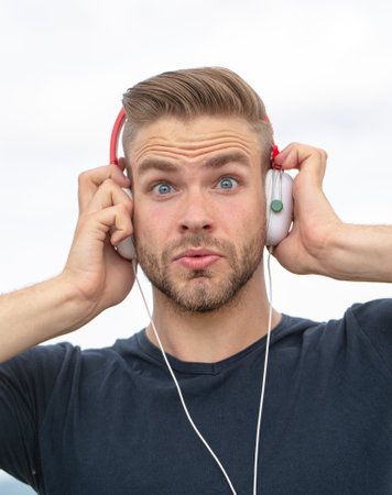 Excited Man listening music in headphones. Emotional surprised portrait guy. Young bearded casual...