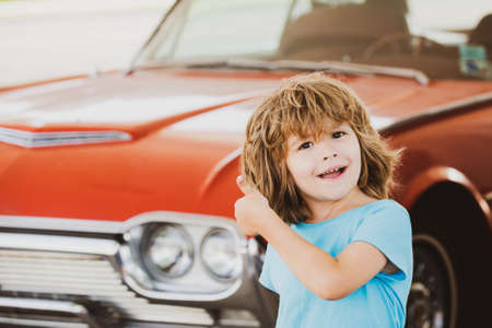 Kid refuel the car. Gas station. Happy boy against red retro automobile.