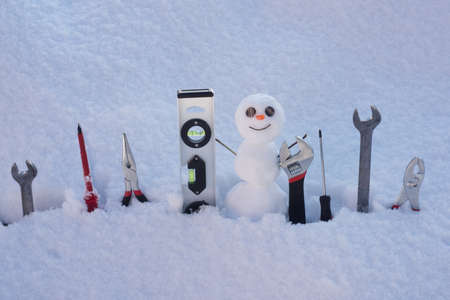Repairing tools. Snowman with repairing instrument. Snow man worker.
