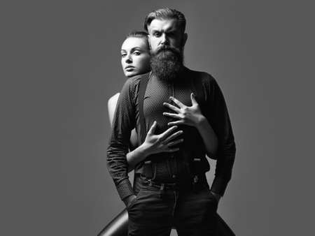 Fashion couple. Pretty girl embraces handsome man hipster with beard and moustache fashion couple on grey background.の写真素材