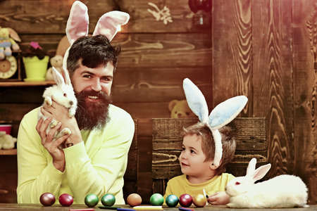 Father and son painting Easter eggs. Rabbits family with bunny ears.