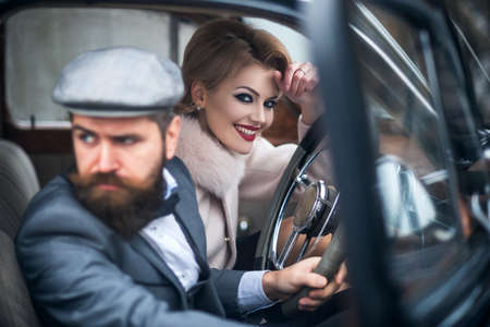 The couple in retro car. Young people together while sitting inside a vintage car.の写真素材