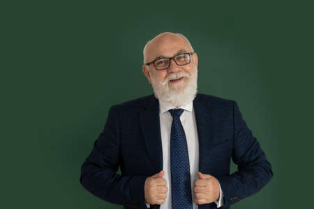 Confident middle-aged male teacher or professor standing in front of a blank chalk board. Funny professor or scientist in a elegant black suit. Teachers day.の写真素材