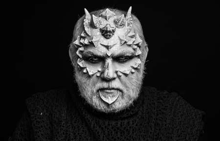 Devil isolated on black. Alien or reptilian makeup with sharp thorns and warts. Horror and fantasy concept. Man with dragon skin and beard. Monster.の写真素材