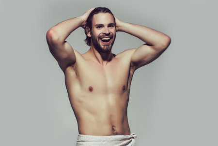 Funny morning shower. Happy nude man in white towel on grey background, wake up.の写真素材