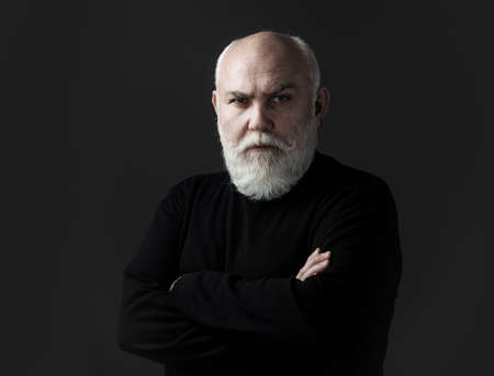 Close up portrait of an elegant senior man with grey hair isolated on black background. Serious Senior Man.の写真素材