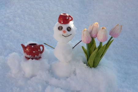Snowman with flowers. Spring winter snow man with coffee cup.の写真素材