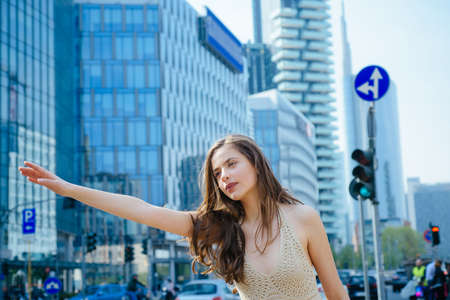 City life, rush time. Hailing taxi concept. Catch taxicar on city street. Travel, tourism and people concept. Woman get a ride.の写真素材