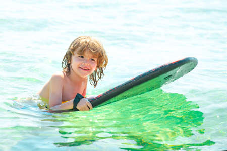 Kid serfer. Catch the wave. Extreme sport activity. Happy child playing in th sea water.の写真素材