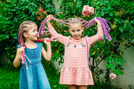 Sister girls with dreadlocks having fun in garden outdoor. Cut best friend pretty child at spring time.の写真素材