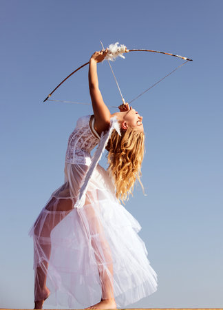 Valentines day. Angel cupid with bow and arrow. Woman in white dress. Portrait of sweet angelic...