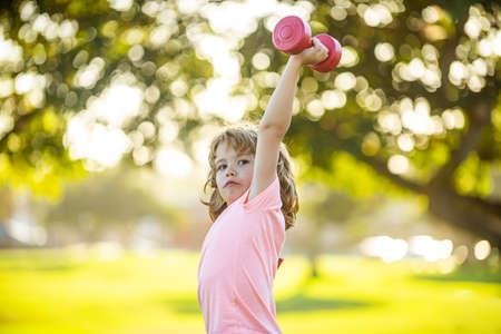 Sporty child with dumbbell outdoor. Kids sport. Boy exercising in park. Active, healthy lifestyle.の写真素材
