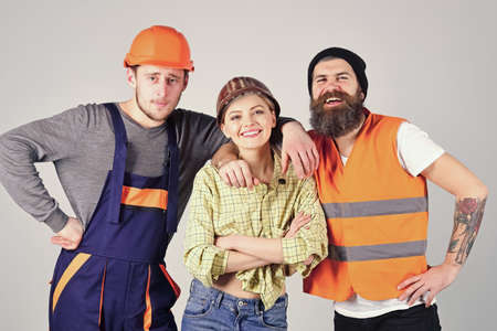 Teamwork, brigade. Company of cheerful workers, builder, repairer, plasterer. Group of man and woman with smiling faces in helmet and boilersuit, grey background.の写真素材