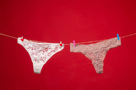 Panties isolated over red. Womans lace panties. Erotic panties hanging on rope. Female lingerie on...