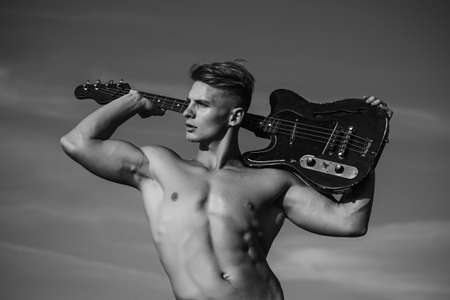 Man with muscular torso hold guitar. Music, performance, entertainment. Athlete guitarist.の写真素材
