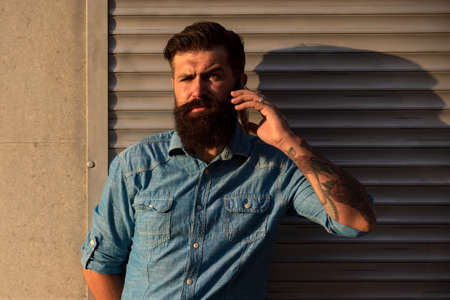 Bearded man talking on phone outdoor. City lifestyle. Communication concept.の写真素材