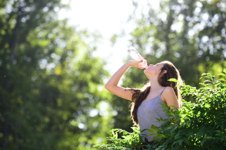Healthy woman drinking water from bottle. Stay hydration concept. Unhidrated. Unity with nature, outdoor.の写真素材