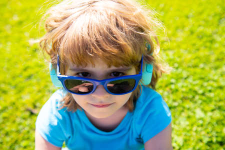 Cute little boy in headphones listening to music on color background.