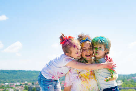 Happy childhood. Portrait of kids in colored powder holi. Kids face painted in the colors. Kids color splash party.の写真素材