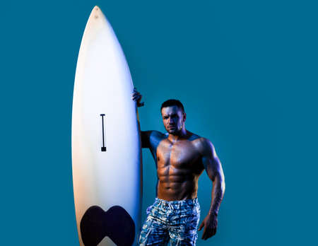 Serfer muscular man with neon surfboard isolated on blue. Male surf with fit body. Sexy surfer with...