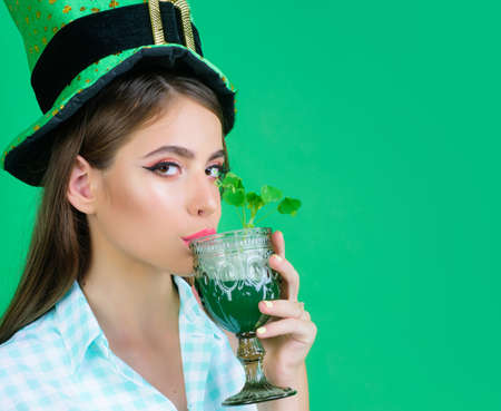 Patricks Day pinup woman in green style. Patricks girl drink cocktail. St Patricks Day celebration. Beautiful woman in green hat. Shamrock leaf.の写真素材