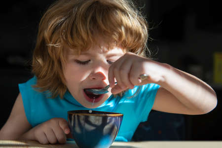 Kids nutrition concept. Healthy home food for children. Boy eats breakfast at kitchen. Organic home...