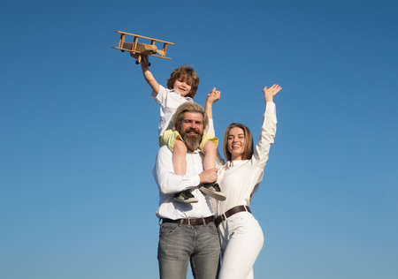 Happy family mother father and child on sky nature. Parents with child. Boy with toy airplane on...