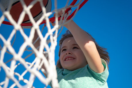 Close up image of kid basketball player making slam dunk during basketball game, stock photo. Banner isolated on sky background.の写真素材