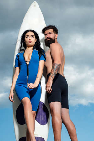 Summer couple vacation. Sexy woman in swimsuit. Summertime concept. Sunbathing. Surfboard.の写真素材