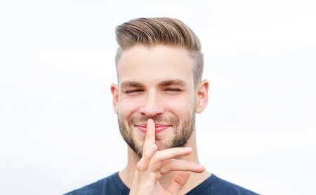 Serious man with finger on lips. Conspiracy, shh. Isolated attractive male shows silence sign.の写真素材