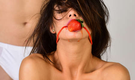 Sexy strawberry in girls mouth. BDSM concept. Gag closeup. Sensual couple play in love games.の写真素材