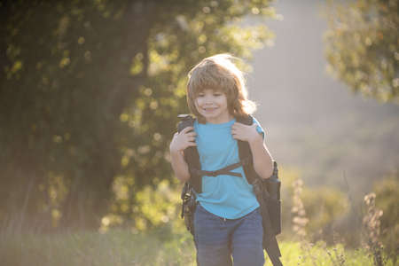 Child hiker with backpack hike in hills background. Cute boy with hiking equipment in the mountains.の写真素材