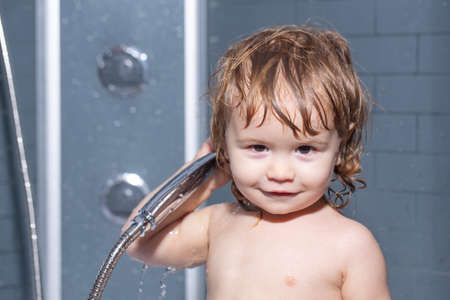 Baby bathes in a bath with foam and soap bubbles. Child bathing under a shower.の写真素材
