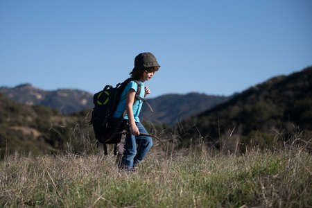 little boy with backpack hiking in scenic mountains. Boy local tourist goes on a local hikeの写真素材