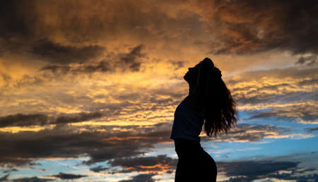 Young woman dancing in summer sunset sky outdoor. People freedom style.の写真素材