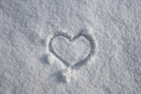 Heart on snow background. Wintertime. White background. Snow texture. Ice snowy background.の写真素材