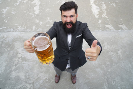 Beard man hold beer from a beer mug. Full length, wide angle. Expression emotions.の写真素材