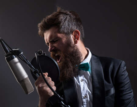 Man with microphone singing song. Musician in music hall. Music festival. Funny guy singing in karaoke.の写真素材