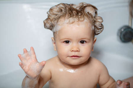 Child in shower. Happy funny baby bathed in the bath. Kid in bathtub with fluffy soap bubble.の写真素材
