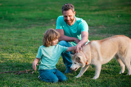 Father and son playing with dog on spring park. Concept of friendly family with pet.