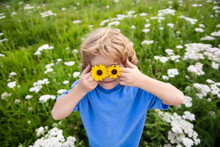 Spring kid. Funny little boy with daisy in eyes.