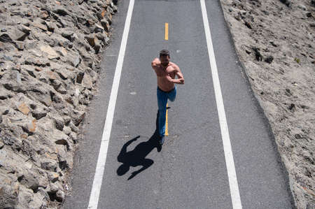 Man with bare torso running on the road. Active healthy runner jogging outdoor.